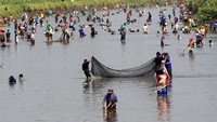 Warga berburu ikan dengan peralatan sederhana saat dilakukan pladu atau flushing (penggelontoran air) Dam Boyolangu, Boyolangu, Tulungagung, Jawa Timur, Minggu (13/08/2023).