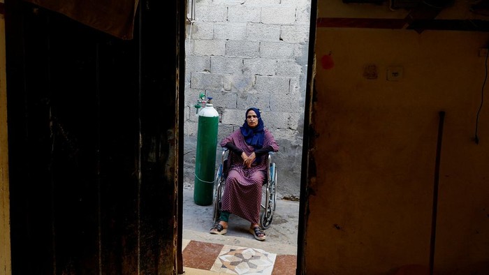 A Palestinian woman, Sabreen Abu Mustafa, struggles for breath outside her house in Khan Younis amid a heatwave in the southern Gaza Strip July 29, 2023. REUTERS/Ibraheem Abu Mustafa
