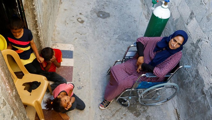A Palestinian woman, Sabreen Abu Mustafa, struggles for breath outside her house in Khan Younis amid a heatwave in the southern Gaza Strip July 29, 2023. REUTERS/Ibraheem Abu Mustafa