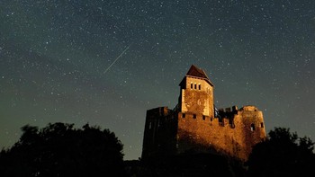 Hujan meteor Perseid terlihat di atas kastil Holloko, Hungaria, Minggu (13/8/2023). (Peter Komka/MTI via AP)