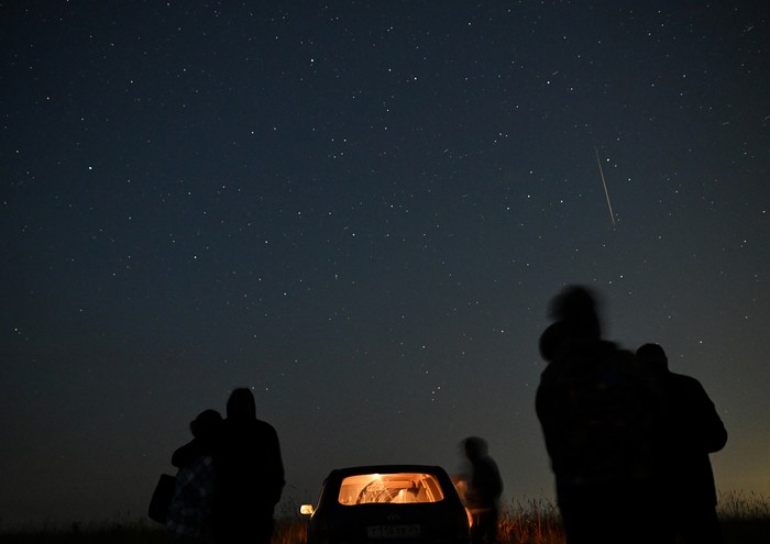 People watch as meteor streaks in the night sky during the annual Perseid meteor shower in the Siberian town of Yeniseysk in the Krasnoyarsk Region, Russia August 12, 2023. REUTERS/Alexey Malgavko