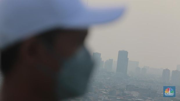 Sejumlah karyawan melihat gedung bertingkat yang tertutup oleh kabut polusi di Jakarta, Senin, (14/8). (CNBC Indonesia/Muhammad Sabki)