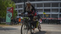 Suporter Arema Malang Miftahuddin Ramly mengendarai sepedanya setiba di Stadion Utama Gelora Bung Karno (SUGBK), Jakarta, Senin (14/8/2023). 