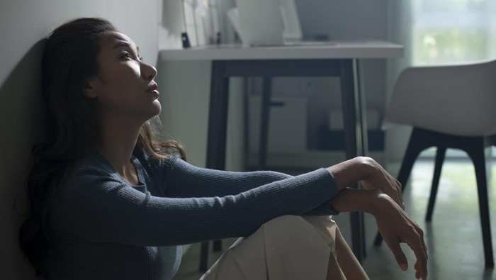 Young Asian woman sitting on floor at home feeling sad tired and worried suffering depression in mental health, problems and broken heart concept, life difficulties