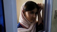 Asra (14) berdiri di depan jendela rumah kontrakan, saat tinggal bersama keluarganya dan menunggu visa khusus mereka yang dibuat oleh pemerintah Barat untuk melindungi warga Afghanistan, di Rawalpindi, Pakistan.  