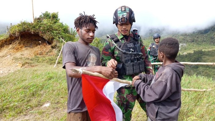Personel Satgas Yonif PR 433/JS bersama anak-anak Kabupaten Nduga memasang bendera putih.