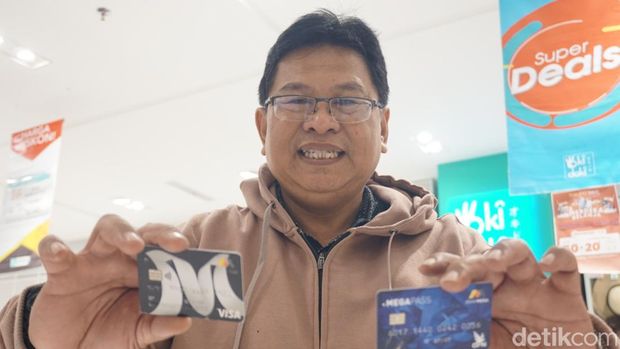 Seorang pelanggan Transmart di Surabaya menunjukkan kartu kredit Bank Mega Syariah usai belanja sepeda listrk di Transmart.