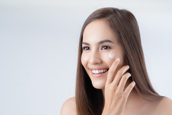 Mirror reflection of woman with skincare cream, spa lotion or dermatology ointment for melasma or acne treatment. Bathroom facial routine, healthcare and face of girl apply cosmetics beauty product