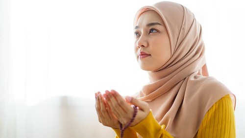 Beautiful Asian young Muslim woman sit on the floor in her house and praying for a holy god - Allah in Islam believe.