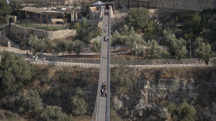 First visitors walk across the longest suspension bridge in Israel, a 202 meter walkway that officials hope will attract tourists, as it opens to the public in Jerusalem, Tuesday, Aug. 15, 2023. The pedestrian bridge stretches between ben Hinnom Valley, surrounding the Old City of Jerusalem, and Mount Zion, a storied hill with religious significance. (AP Photo/Ohad Zwigenberg)