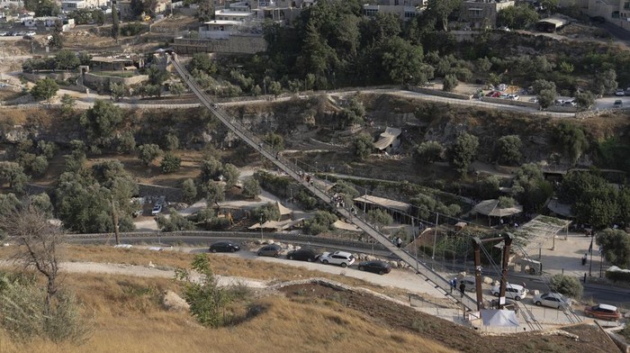 First visitors walk across the longest suspension bridge in Israel, a 202 meter walkway that officials hope will attract tourists, as it opens to the public in Jerusalem, Tuesday, Aug. 15, 2023. The pedestrian bridge stretches between ben Hinnom Valley, surrounding the Old City of Jerusalem, and Mount Zion, a storied hill with religious significance. (AP Photo/Ohad Zwigenberg)