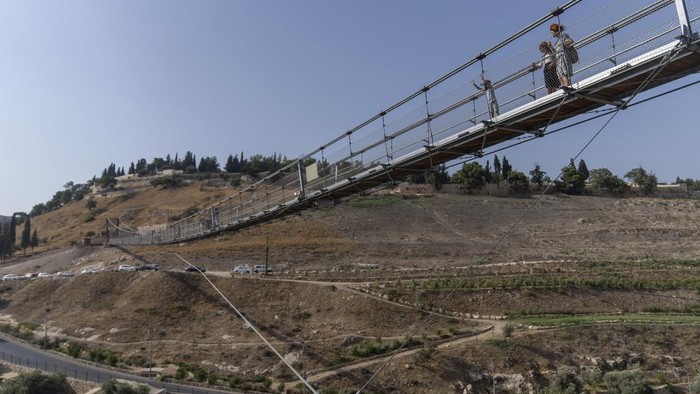 First visitors walk across the longest suspension bridge in Israel, a 202 meter walkway that officials hope will attract tourists, as it opens to the public in Jerusalem, Tuesday, Aug. 15, 2023. The pedestrian bridge stretches between ben Hinnom Valley, surrounding the Old City of Jerusalem, and Mount Zion, a storied hill with religious significance. (AP Photo/Ohad Zwigenberg)