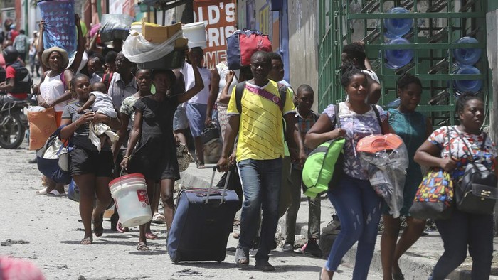 Residents flee their homes to escape clashes between armed gangs in the Carrefour-Feuilles district of Port-au-Prince, Haiti, Tuesday, Aug. 15, 2023. (AP Photo/Odelyn Joseph)