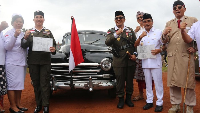 Bupati Tabanan I Komang Sanjaya dan istrinya mengapit mobil Plymouth De Luxe yang sempat menjadi milik Fatmawati Soekarno  di Lapangan Debes, Tabanan, Bali, Kamis (17/8/2023). (chairul amri simabur/detikBali)