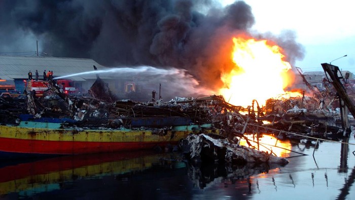 Suasana kapal yang masih terbakar di Pelabuhan Jongor, Tegal, Jawa Tengah, Kamis (17/8/2023). Menurut Himpunan Nelayan Seluruh Indonesia (HNSI) Jawa Tengah pada hari ketiga jumlah kapal nelayan yang terbakar bertambah dari 61 menjadi 63 kapal dan hingga saat ini sebagian kapal masih mengeluarkan api didselimuti asap hitam.