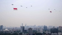 Sejumlah helikopter mengudara di langit Jakarta sambil mengibarkan bendera merah putih. 