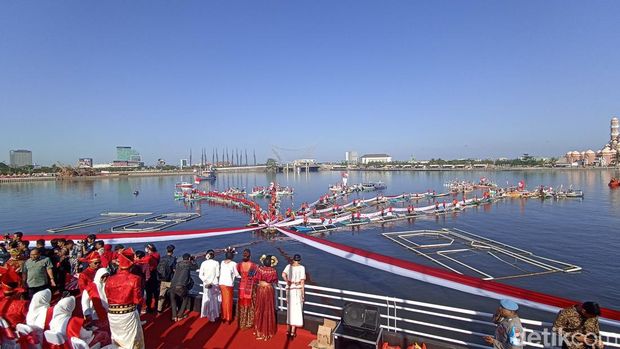 Pembentangan bendera merah putih berbentuk bunga rampai di Pantai Losari Makassar.