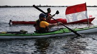 Para pendayung melakukan parade sambil mengibarkan bendera merah putih. 
