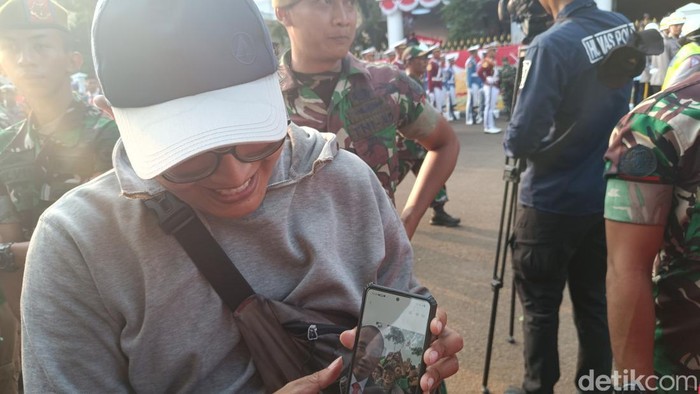 Senyum sumringah Erlan saat tunjukkan foto selfie bareng Jokowi (Rizky/detikcom).
