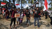 Warga menunjukkan beragam hadiah lomba panjat pinang. 