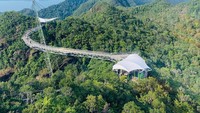 Jembatan Layang Langkawi, Malaysia. Dengan dimensi mencapai 125 meter (sekitar 410 kaki), Jembatan Layang Langkawi berhasil mengukuhkan posisinya sebagai jembatan gantung melengkung tanpa penyangga terpanjang di seluruh dunia. Terletak di puncak Gunung Machinchang, jembatan pejalan kaki ini dirancang oleh Peter Wyss dan digantungkan dari delapan kabel dengan ketinggian sekitar 100 meter (sekitar 328 kaki) di atas tanah. Setelah melalui peremajaan menyeluruh pada tahun 2012, jembatan ini kembali dibuka untuk umum pada tahun 2015. Akses ke jembatan ini hanya dapat dilakukan melalui gondola, dan desainnya diperkaya dengan titik-titik pandang yang memungkinkan para pengunjung menikmati pemandangan lanskap yang penuh dengan dramatisasi, dihiasi oleh rimbunnya pepohonan yang membingkai panorama tersebut. dok. www.tripadvisor.com.au.  