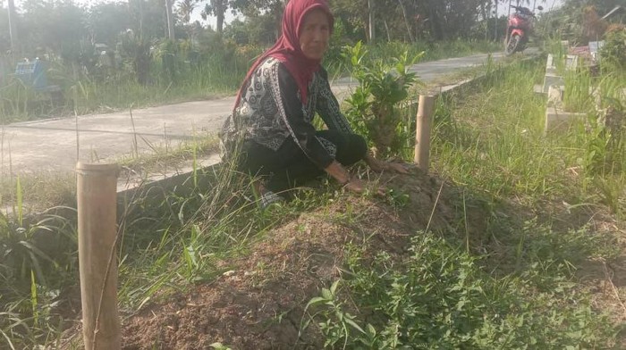 Tuminah di samping makan suaminya, Damikun Madsaidi (70) yang meninggal akibat komplikasi organ.