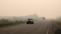 Kendaraan pengungsi menembus tebalnya asap yang ditimbulkan oleh kebakaran hutan. Reuters/Pat Kane. 