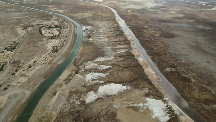 A picture taken on August 15, 2023 shows patterns formed by crystalized minerals and sinkholes on the surface of a dried-up Dead Sea area which exposed and created a salt plain, near the southern Israeli Neve Zohar Resort. The Dead Sea has lost a third of its surface area since 1960 with the blue water receding about a metre (yard) every year, leaving behind a lunar landscape whitened by salt and perforated with gaping holes. (Photo by MENAHEM KAHANA / AFP)