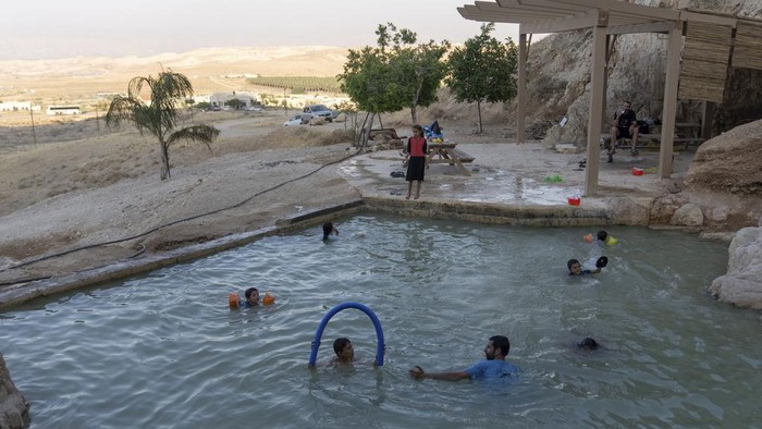Israeli children swim in a pool at the Jewish settlement of Mevo'ot Yericho, in the Jordan Valley near the Palestinian city of Jericho, Friday, Aug. 11, 2023. In the occupied West Bank, where Israeli water pipes don’t reach, Palestinians say they can't get enough water to irrigate their farms. By comparison, the neighboring Jewish settlements look like an oasis with swimming pools. (AP Photo/Ohad Zwigenberg)
