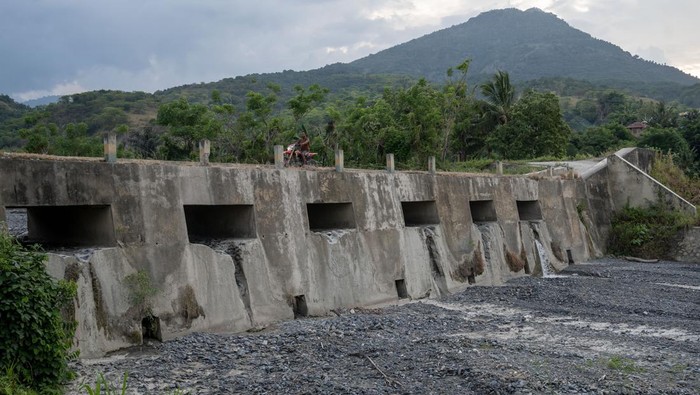 Penurunan debit air di cekdam Balane Pengendara sepeda motor melintas di atas cekdam Balane di Desa Balane, Sigi, Sulawesi Tengah, Jumat (18/8/2023). Cekdam yang selain berfungsi sebagai pengendali banjir, juga sebagai sumber air baku bagi warga sekitar dan pengairan bagi lahan pertanian itu mengalami penurunan debit air yang signifikan sejak sebulan terakhir akibat kemarau. ANTARA FOTO/Basri Marzuki/tom.