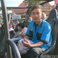 Kemeja Gibran hadir dalam warna biru dengan aksen hitam, lengkap beratribut nama ‘Mas Gibran dan Petugas Parkir di pundak. Kancingnya dibiarkan terbuka sehingga terekspos kaus hitam di baliknya. Adapun celana kargo jadi andalan untuk bawahan. (Foto: Tara Wahyu NV/detikJateng)