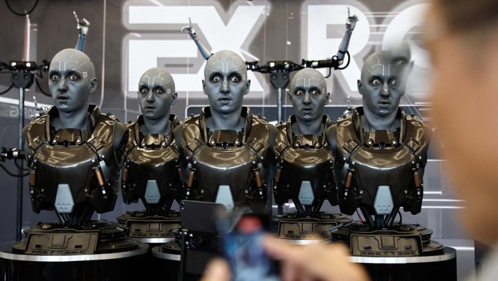 A visitor stands near robotic welding arms used in car production developed by Siasun, at the Beijing World Robot Conference (WRC) 2023 in Beijing, China, August 17, 2023. REUTERS/Tingshu Wang