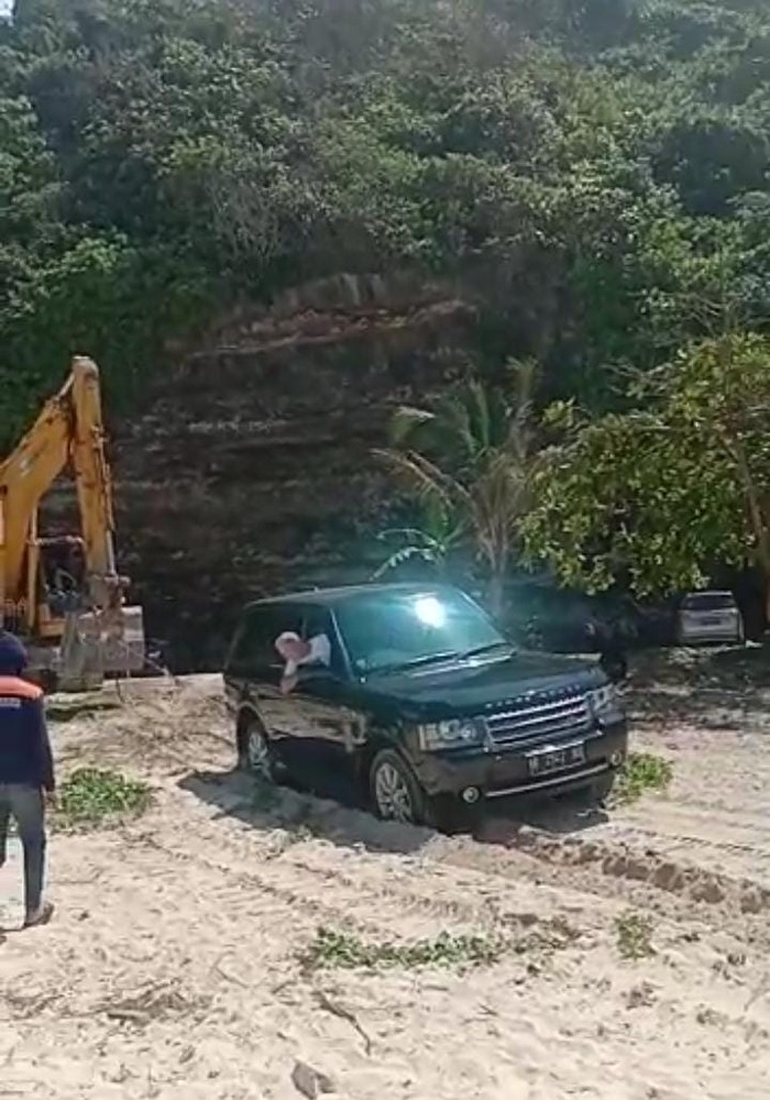 Mobil hitam terjebak di pasir Pantai Timbis ditarik eskavator, Sabtu (19/8/2023). (Foto: Istimewa)