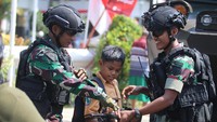 Seorang pelajar memegang senjata didampingi dua orang prajurit TNI AD saat pameran alutsista di Kota Kediri, Jawa Timur, Sabtu (19/8/2023).