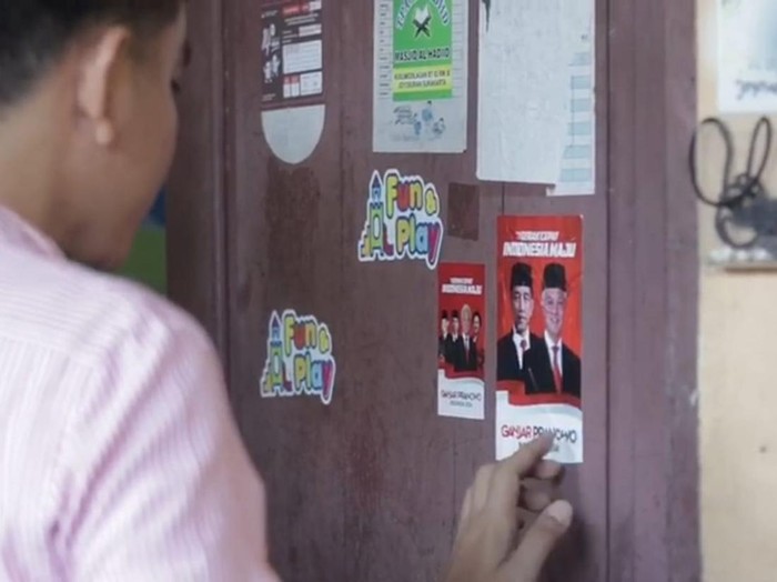 Wali Kota Solo Gibran Rakabuming Raka, menempel stiker bergambar Jokowi-Ganjar saat blusukan di RW 11 Joyosuran, Kecamatan Pasar Kliwon, Kota Solo, Sabtu (19/8/2023).