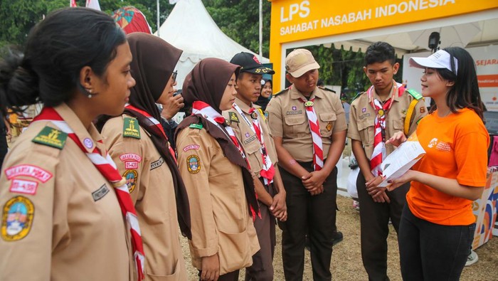 Pekerja menerangkan kepada sejumlah Pramuka mengenai LPS pada peringatan Hari Indonesia Menabung tahun 2023 di Bumi Perkemahan Cibubur, Minggu (20/8/2023).