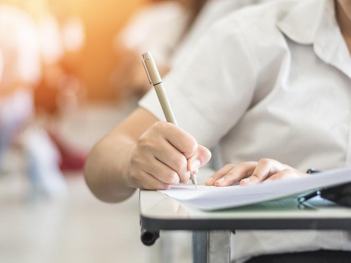 Exam with school student having a educational test, thinking hard, writing answer in classroom for  university education admission and world literacy day concept