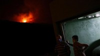 Dua orang warga bersiaga di depan rumahnya. Sesekali mereka melihat ke arah hutan yang terbakar.