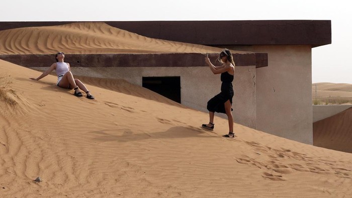 People visit the Bedouin village of al-Ghuraifabout, buried under the sand, 100 km, 62 miles, southeast of Sharjah, United Arab Emirates, Sunday, July 9, 2023. Built-in the 1970s, the village was abandoned two decades later as oil wealth transformed the country into a global hub of commerce and tourism, home to the futuristic cities of Dubai and Abu Dhabi. (AP Photo/Kamran Jebreili)
