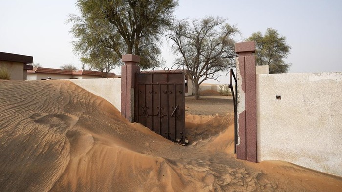 People visit the Bedouin village of al-Ghuraifabout, buried under the sand, 100 km, 62 miles, southeast of Sharjah, United Arab Emirates, Sunday, July 9, 2023. Built-in the 1970s, the village was abandoned two decades later as oil wealth transformed the country into a global hub of commerce and tourism, home to the futuristic cities of Dubai and Abu Dhabi. (AP Photo/Kamran Jebreili)