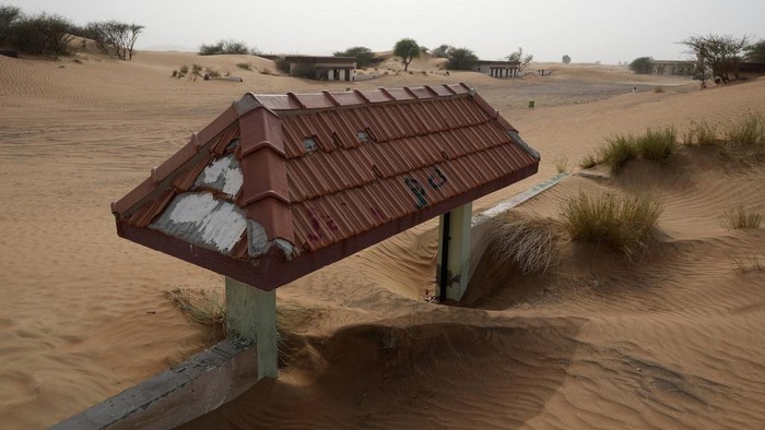 Menyusuri Desa Hantu di Gurun Dubai People visit the Bedouin village of al-Ghuraifabout, buried under the sand, 100 km, 62 miles, southeast of Sharjah, United Arab Emirates, Sunday, July 9, 2023. Built-in the 1970s, the village was abandoned two decades later as oil wealth transformed the country into a global hub of commerce and tourism, home to the futuristic cities of Dubai and Abu Dhabi. (AP Photo/Kamran Jebreili)