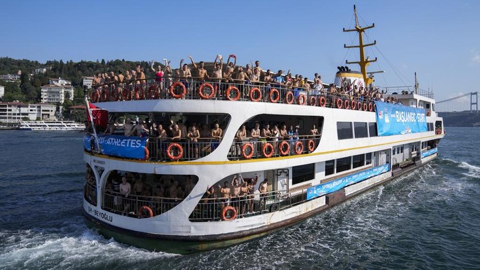 Semangat Peserta Ikut Lomba Renang Lintas Benua di Turki Competitors travel to the start line of a 6.5km swimming race across the Bosporus Strait, from the Asian side to the European side, in Istanbul, Turkey, Sunday, Aug. 20, 2023. (AP Photo/Khalil Hamra)