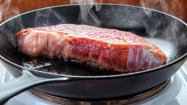 Steak Searing beef brisket steak on the electric stove with hot cast iron skillet
