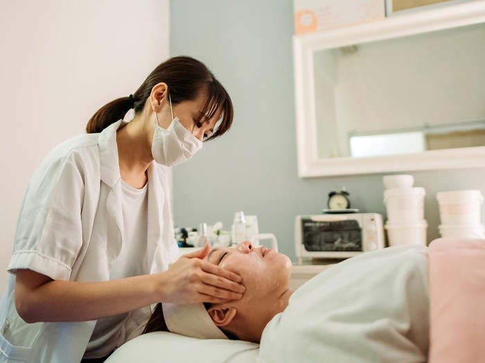 beautician applying mask for female customer