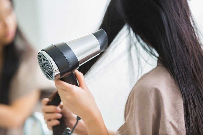 Woman with a hair dryer to heat the hair.