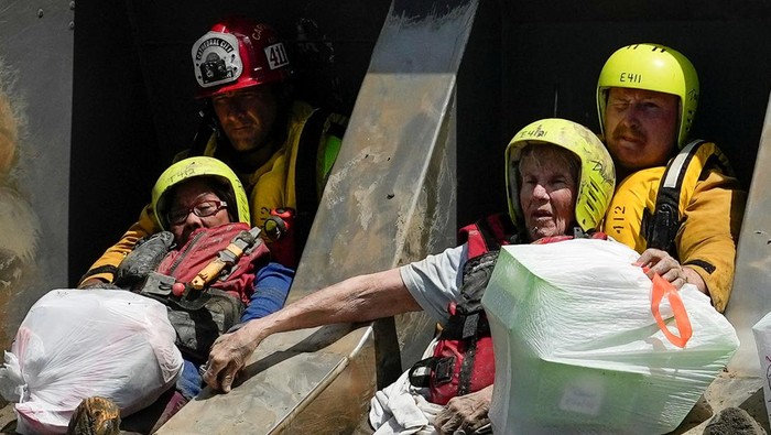 Momen Evakuasi Penghuni Panti Jompo yang Terdampak Badai Hilary Firefighters and emergency medical personnel transport a resident, who had been trapped overnight in a care home, to an ambulance following Tropical Storm Hilary in Cathedral City, California, U.S., August 21, 2023. REUTERS/Bryan Woolston