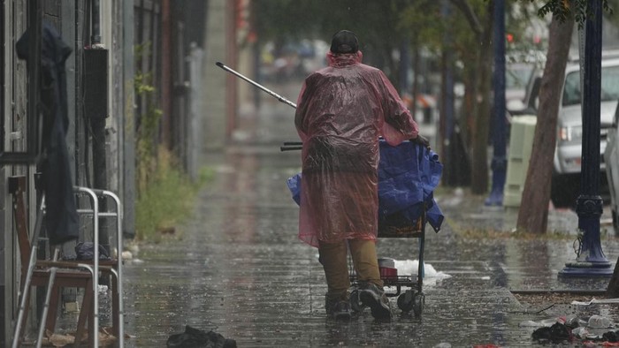 Nestapa Tunawisma di California Saat Badai Hilary Menerjang Homeless people carry a plastic tarp to shield themselves from a light rain brought by Tropical Storm Hilary in downtown San Diego, Sunday, Aug. 20, 2023. (AP Photo/Damian Dovarganes)
