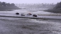 Kendaraan melintasi cekungan pengendali banjir yang hampir mencapai jalan, Minggu, (20/8/2023), di Palm Desert, California. Para ilmuwan memperkirakan El Nino alami, perubahan iklim yang disebabkan manusia, kubah panas yang membandel di atas negara bagian tengah tubuh dan faktor-faktor lain membuat terobosan Hilary yang memecahkan rekor ke California dan Nevada. AP/Mark J. Terrill
