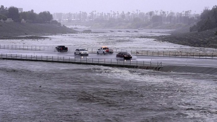 Potret California Diamuk Badai Hilary Vehicles cross over a flood control basin that has almost reached the street, Sunday, Aug. 20, 2023, in Palm Desert, Calif. Forecasters said Tropical Storm Hilary was the first tropical storm to hit Southern California in 84 years, bringing the potential for flash floods, mudslides, isolated tornadoes, high winds and power outages. (AP Photo/Mark J. Terrill)