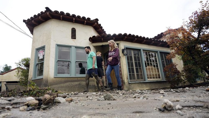 Residents walk outside of their neighbor's mud-filled home in the aftermath of Tropical Storm Hilary Monday, Aug. 21, 2023, in Yucaipa, Calif. (AP Photo/Marcio Jose Sanchez)